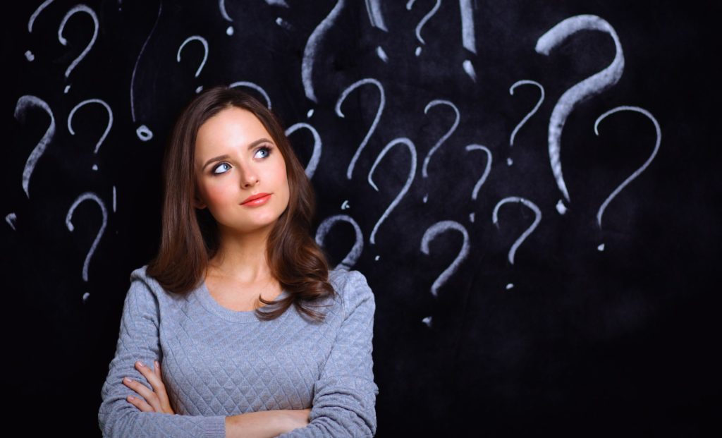 Young girl with question mark on a gray background .
